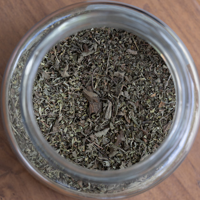 Glass jar filled with dried herbs on a wooden surface