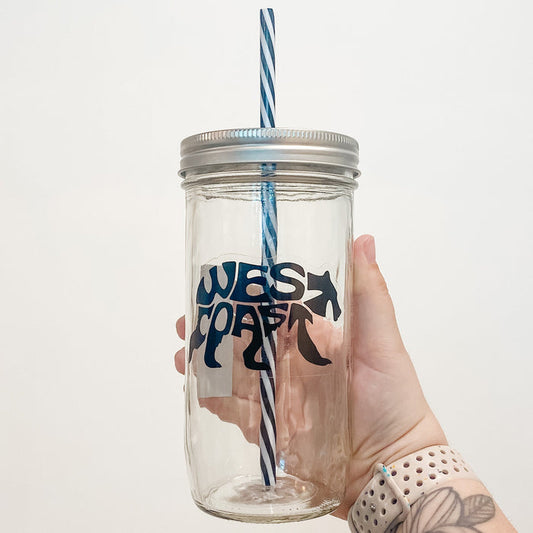 Hand holding mason jar that reads west coast in black text and shape of bear with clear background.