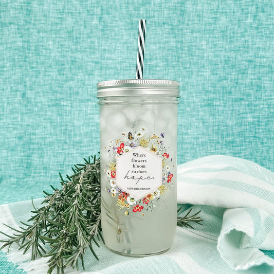 Mason jar tumbler that says “Where flowers bloom so does hope. Lady Bird Johnson” with flowers and butterflies creating a hexagon around the quote.