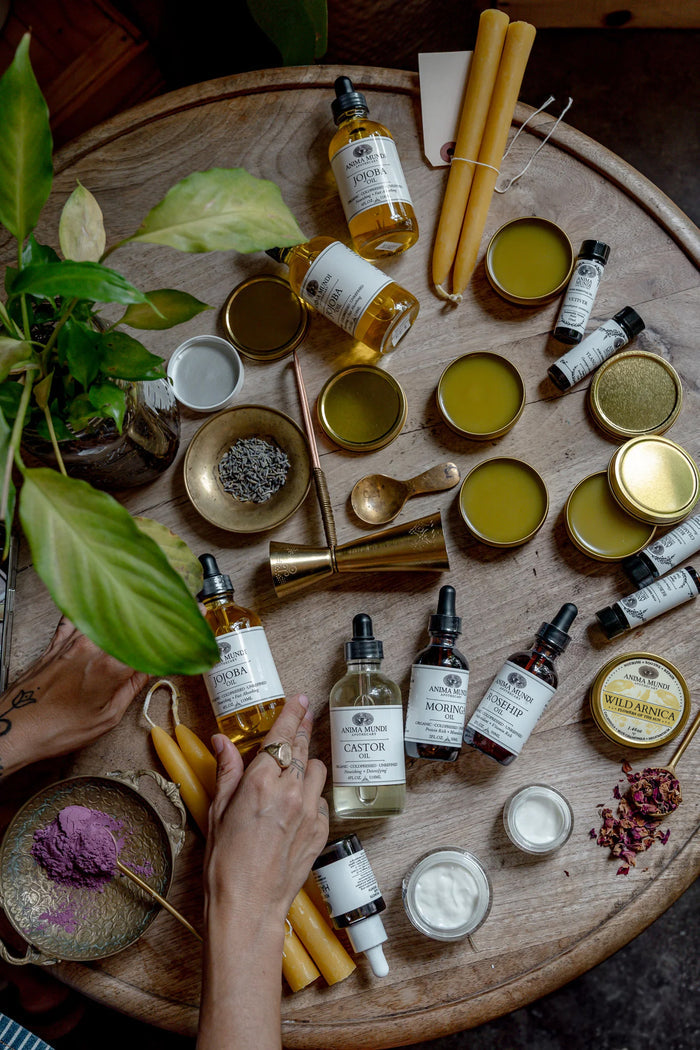 Wooden table with skincare products, including bottles and jars, with a hand reaching out.